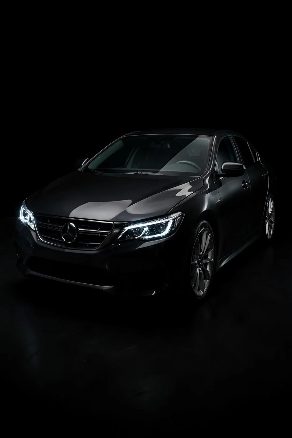 Sedan premium em estúdio escuro com faróis acesos